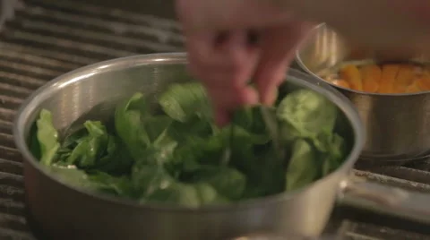 Spinach being tossed in a pan by a chef in a kitchen Stock Footage 58443433