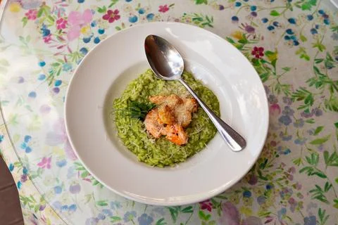 Spinach risotto with shrimp and scallops on a white plate, top view Stock Photos