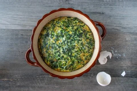 Spinach souffle in rustic round dish with egg shells flat lay Stock Photos