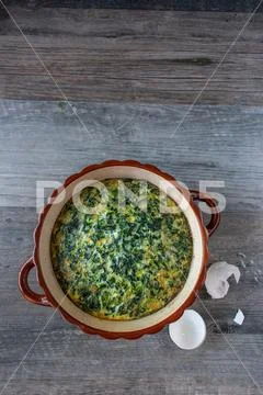 Spinach souffle in rustic round dish with egg shells flat lay Stock Photos