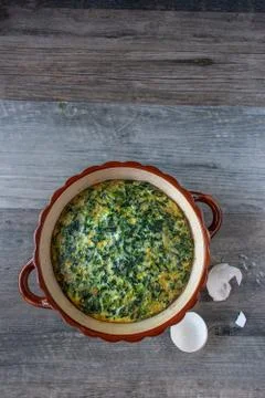 Spinach souffle in rustic round dish with egg shells flat lay Stock Photos