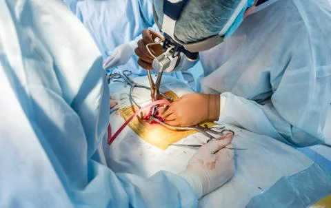 Spinal surgery. Group of surgeons in operating room with surgery equipment. Stock Photos