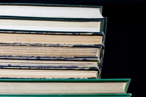 The spines of old books lying on the stack. Books stacked on an old table. Stock Photos