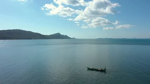 Spinning around by drone moving long boat in shallow water of ocean next to isla Stock Footage 124415243