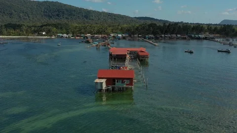 Spinning around red floating old wooden house in sea water connected by long pie Stock Footage 124415857