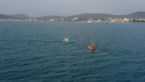 Spinning around two boats getting separated in sunset next to island above ocean Video stock 124107300