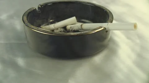 Spinning ashtray with smoking cigarette and cigarette butts Stock Footage