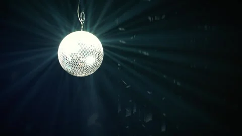 Spinning disco ball creating light rays through smoke in dark Stock Footage 346332163