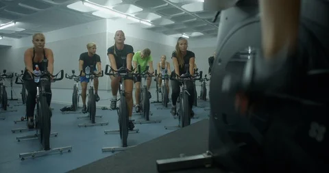 A Spinning Instructor leads a class of mixed people on exercise bikes. 库存影片 85535159