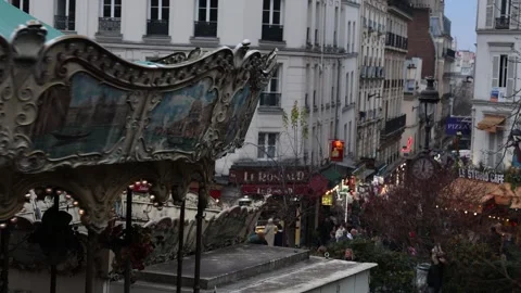 Spinning merry go round carousel in Paris arts neighborhood, establishing b Stock Footage 328717736