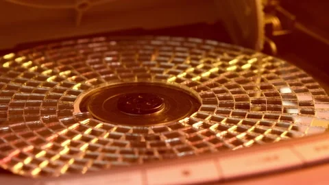 Spinning mirrored CD reflects warm nostalgic glow inside vintage tray, capturing Video stock 305573937