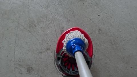 Spinning mop in red bucket on concrete garage floor Stock Footage 346077064