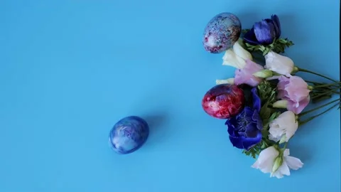 Spinning painted egg and spring bouquet on blue background Stock Footage 234890762