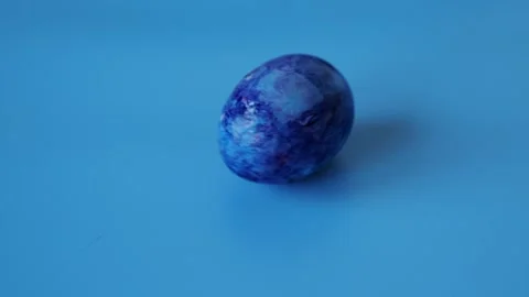 Spinning painted egg on blue background Stock Footage 263042026