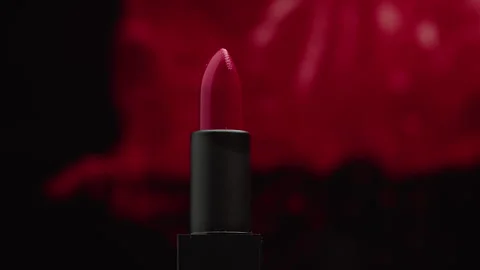 Spinning red lipstick on a red painted background as a presentation of cosmetics Stock Footage 263976216