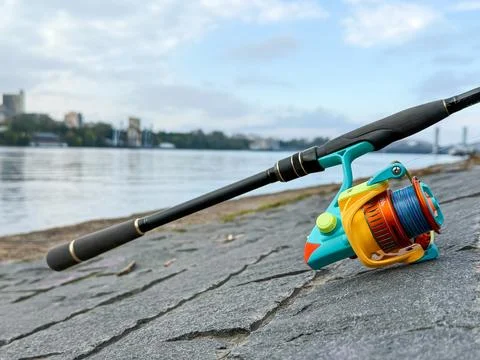 Spinning rod, lying on the background of a river or lake Stock Photos