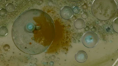 Spinning shot of oil bubbles mixed with paint and glitter in murky water Video stock 208750215