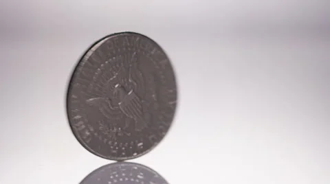 Spinning US half dollar coin on white surface, in slow motion Stock Footage