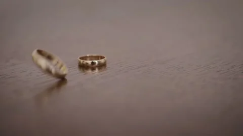 Spinning wedding rings. Rotating rings of groom and bride on the table Stock Footage 132693713