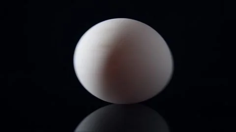 Spinning the white raw egg on black background, Low contrast light Stock Footage 146394117