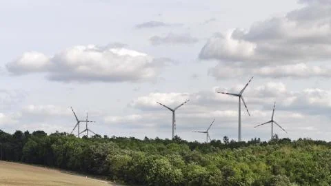 Spinning wind generators above trees Stock Photos