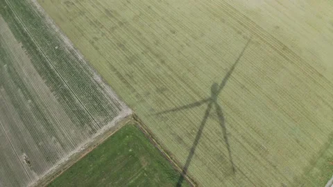 Spinning wind turbine casting a long shadow onto a field in the Netherlands.. Stock Footage 231488153