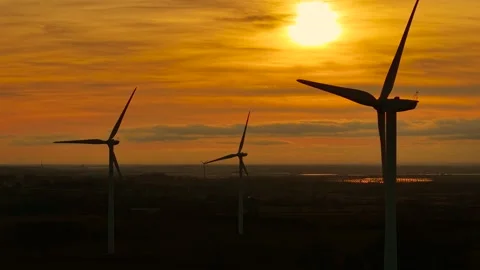 Spinning wind turbines generating clean energy in sunset glow. Rotating blades Stock Footage 312784391