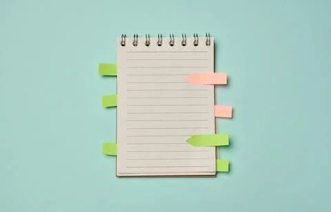 Spiral-bound lined notebook with colorful sticky index tabs on a turquoise .. Stock Photos