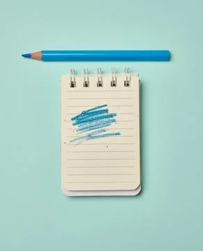 Spiral-bound lined notepad with a blue scribbled stroke and a blue pencil o.. Stock Photos