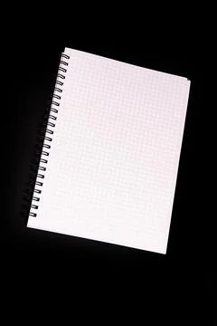 Spiral-bound notebook on graph paper against black background, presenting cle Stock Photos