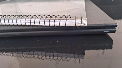 Spiral bound notebook resting on top of a closed black laptop Stockfoto's