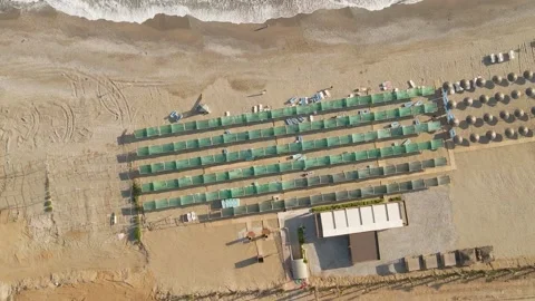 Spiral flight over the hotel's tourist beach with sunbeds and awnings Video stock 194683053
