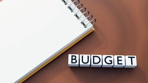 A spiral notebook and white blocks  spell out the word "BUDGET". Ilustração Stock