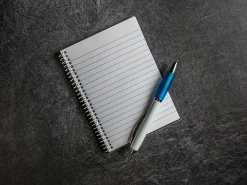 Spiral notebook with empty page and pen on a dark slate background copy space Stock Photos