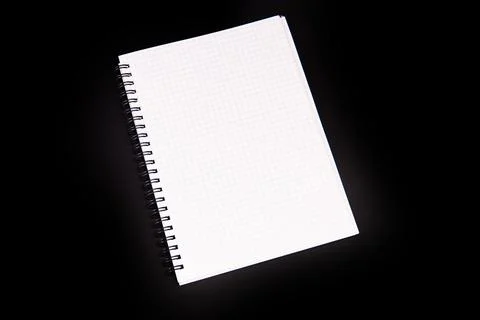 Spiral notebook with graph paper pages positioned diagonally on a stark black Stock Photos