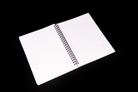 Spiral notebook open on graph paper pages, positioned diagonally against blac Stock Photos