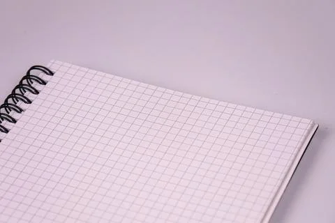 Spiral notebook open on grid pages, black metal binding, clean minimalistic s Stock Photos