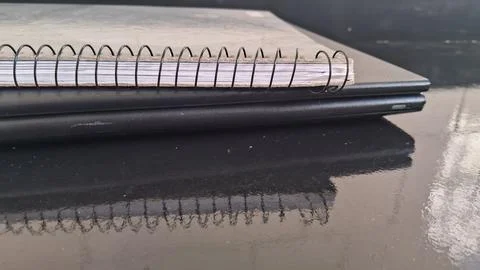 Spiral notebook resting on a closed black laptop computer surface Stock Photos