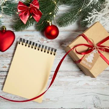 Spiral notepad and gift box on wooden background with christmas decorations Stock Photos