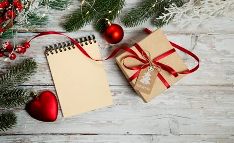Spiral notepad and gift box on wooden background with christmas decorations Stock Photos