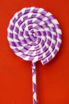 Spiral-patterned lollipop on red surface Stock Photos