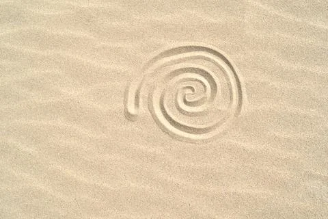 Spiral shell drawn on the sand on the beach top view with copy space Stock Photos