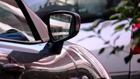 Spiral wind spinner reflecting on the wing mirror of a black modern car Stock Footage 139104943