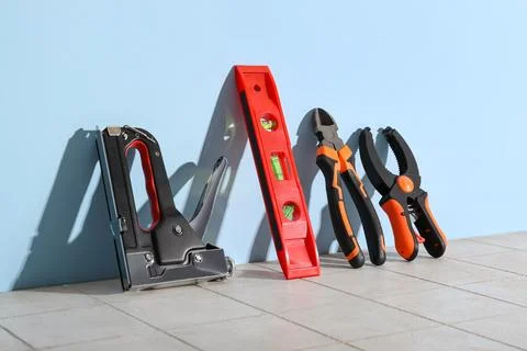 Spirit level and tools leaned against blue wall Stock Photos