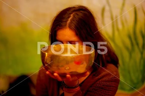 Spiritual girl immersed in meditative sounds of tibetian bowl. Stock Photos