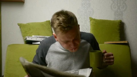 Spitting tea onto paper while reading fake news by young man indoors 库存影片 92946959