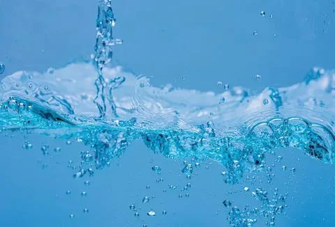 Splash of clear blue water with bubbles and ripples Stock Photos