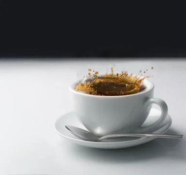 Splash of coffee in white cup Stock Photos