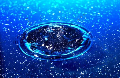 Splash - a drop falling onto the water surface in a color macro shot Stock Photos