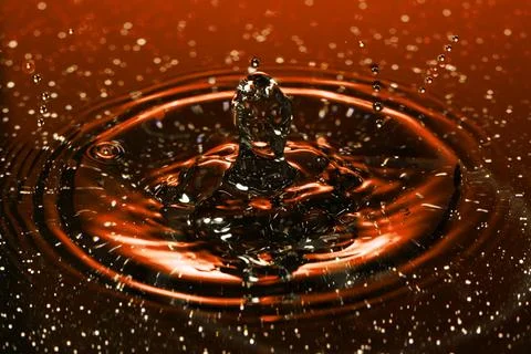 Splash - a drop falling onto the water surface in a color macro shot Stock Photos